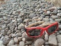 children's glasses, red frames with dark glass lying on small pebbles Royalty Free Stock Photo