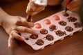 Children& x27;s hands squeeze using pastry bag filling hot melt chocolate into silicone mold.  Selective focus Royalty Free Stock Photo