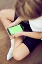 Children& x27;s hands using a phone with a green screen. A little girl is sitting on the floor and holding a smartphone