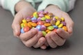 Children& x27;s palms hold a bunch of candies of different colors, glazed candies front view, round delicacies. Royalty Free Stock Photo