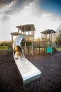 Children's playground wooden play structure fort with large metal slide and climbing wall with grips Royalty Free Stock Photo