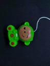 a children's toy in the form of a green frog animal character made of plastic with a black background