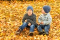 Children in yellow and gold autumn forest. Two little brothers on leafs in fall park. Family walk outdoor. Friendly relationship Royalty Free Stock Photo
