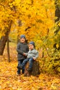 Children in yellow and gold autumn forest. Two little brothers on a wooden stump in fall park. Family walk outdoor. Friendly Royalty Free Stock Photo