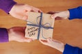 Childrens hands and daddy hands holding a gift or present box with kraft paper and tied blue ribbon tag on Happy fathers day Royalty Free Stock Photo