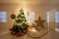 Childrens room with decorated christmas tree and presents. Christmas evening. White room with stucco. Royalty Free Stock Photo