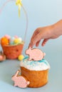 A childs hand holds a pink gingerbread in the shape of a rabbit on an Easter cake Royalty Free Stock Photo