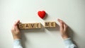 Childs hand putting heart sign and save me phrase made of wooden cubes, charity