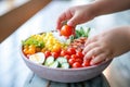 childs hand reaching for a cherry tomato in a cobb salad