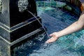 A childs hand recieving water from a lion head water fountain.