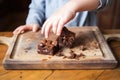 childs hand taking a piece of brownie from a wooden tray