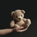 A childs hand tightly gripping a teddy bear with comforting words attached to it. Psychology emotions concept. AI