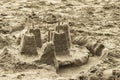 Childs sand castle made from molds with sticks for flags on top and a moat abandoned on the beach - selective focus