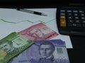 chilean banknotes, pen and calculator on background with rising trend green line