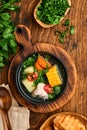 Chilean meat soup with pampkin, corn, fresh coriander and potatoes on old wooden table background. Cazuela. Latinamerican food.