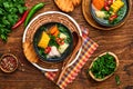 Chilean meat soup with pampkin, corn, fresh coriander and potatoes on old wooden table background. Cazuela. Latinamerican food