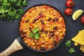 Chili con carne with beef, red beans, paprika, sweet corn and hot peppers in tomato sauce, spicy tex-mex dish in frying pan, black Royalty Free Stock Photo