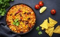 Chili con carne with beef, red beans, paprika, sweet corn and hot peppers in tomato sauce, spicy tex-mex dish in frying pan, black Royalty Free Stock Photo