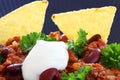 Chili con carne meal in a rustic bowl. Traditional dish of mexican cuisine with kidney beans, minced meat, parsley, tortilla chips Royalty Free Stock Photo