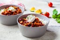 Chili con carne with rice in gray bowl. Beef stew with beans in tomato sauce with sour cream and rice. Traditional Mexican food