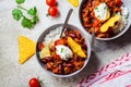 Chili con carne with rice, sour cream and nachos in gray bowl. Beef stew with beans, tomato sauce, sour cream and rice.