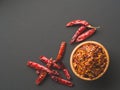 Chili flakes in the wooden bowl and dried peppers on black papper background. Dried and crushed fruits of Capsicum Royalty Free Stock Photo