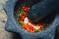 Chili pepper garlic pound mixed in mortar, Thai traditional kitchen tool. Royalty Free Stock Photo