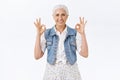 Chill, unbothered happy old woman with grey haircut, wear denim vest, dress, showing everything okay, ok gesture