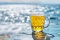 Chilled beer mug on the blue wooden table. Blurred sea is at the background Royalty Free Stock Photo