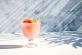 A chilled drink with grapefruit or red orange in glasses on a gray background under the shadow of palm leaves. Summer Royalty Free Stock Photo