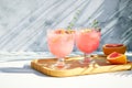 A chilled drink with grapefruit or red orange in glasses on a gray background under the shadow of palm leaves. Summer Royalty Free Stock Photo