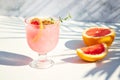 A chilled drink with grapefruit or red orange in glasses on a gray background under the shadow of palm leaves. Summer Royalty Free Stock Photo