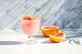 A chilled drink with grapefruit or red orange in glasses on a gray background under the shadow of palm leaves. Summer Royalty Free Stock Photo