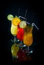 chilled fruity cocktails on a black mirrored background with slices fruits