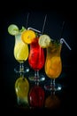 chilled fruity cocktails on a black mirrored background with slices fruits