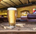 Chilled glass of light beer and wheat on old wooden table