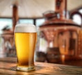 Chilled glass of light beer on wooden table and blurred copper brewing system at the background Royalty Free Stock Photo