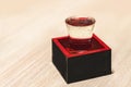 Japanese rice wine in a sake-serving glass inside a lacquered wooden masu box.