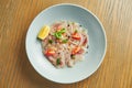 Chilled sea bass carpaccio with red onion, cherry tomatoes and hot chili peppers in a beige bowl on a wooden background. Close up Royalty Free Stock Photo