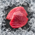 Chilled tuna steak on stone black slate serving plate and ice cubes arranged as a frame. Top view Royalty Free Stock Photo