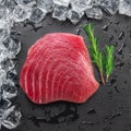 Chilled tuna steak on stone black slate serving plate and ice cubes arranged as a frame. Top view Royalty Free Stock Photo