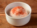 Chilli peru ice cream scoop topped with chilli powder served in a bowl over a rustic wooden table, selective focus