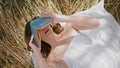 Chilling brunette covering face book at wheat field closeup. Lady peeping camera Royalty Free Stock Photo