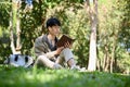 Chilling and focused young Asian male college student reading a book in the park Royalty Free Stock Photo