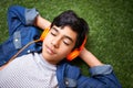 Chilling out with his favorite tunes. A young boy relaxing on the lawn and listening to music. Royalty Free Stock Photo