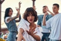 Chilling out. Pretty and young woman in white shirt is dancing and looking at camera while standing on rooftop terrace