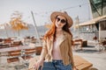 Chilling young woman in casual outfit looking through sunglasses with smile sitting on table. Outdoor portrait of Royalty Free Stock Photo