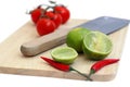 chillis, lime and tomato on a chopping board and the knife isolated Royalty Free Stock Photo