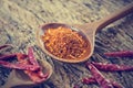 Chilly powder with red dried chilies in wooden spoon on old wooden