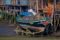 CHILOE, CHILE - SEPTEMBER, 27, 2018: Boat in low tide in front of colorful wooden building palafitos at sunny day in